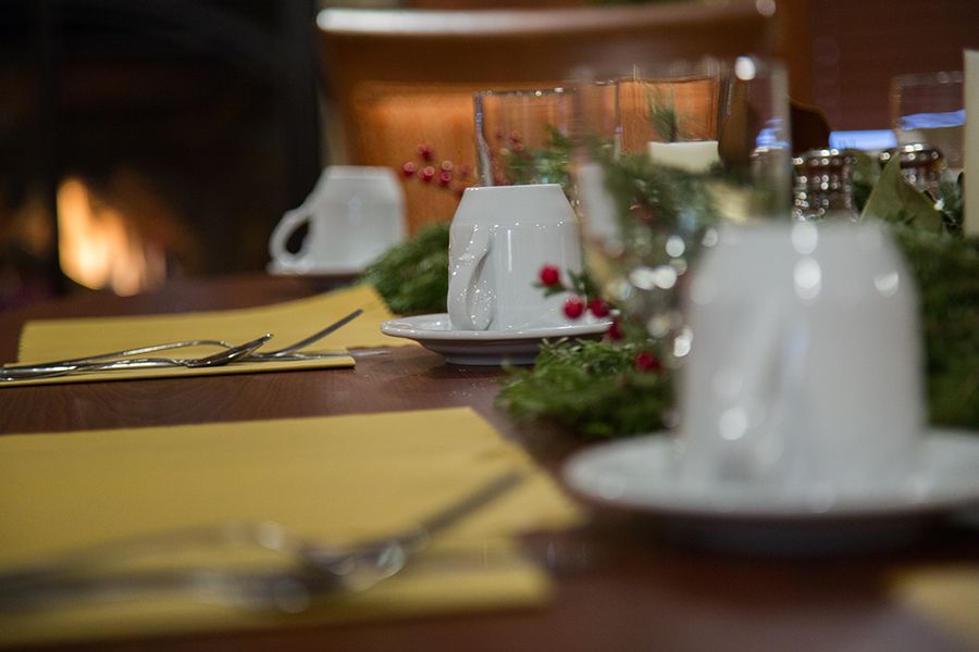 A festive dining table set with cups, napkins, cutlery, and holiday decorations.