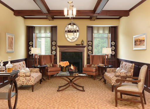 A cozy and elegantly designed living room featuring comfortable armchairs, a central coffee table, and a warm fireplace.