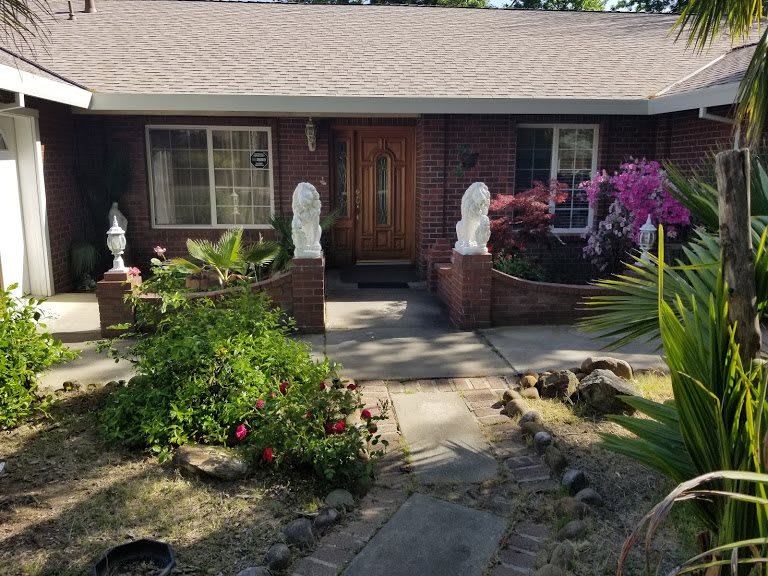A quaint house with a well-maintained garden featuring sculptures and colorful flowers.