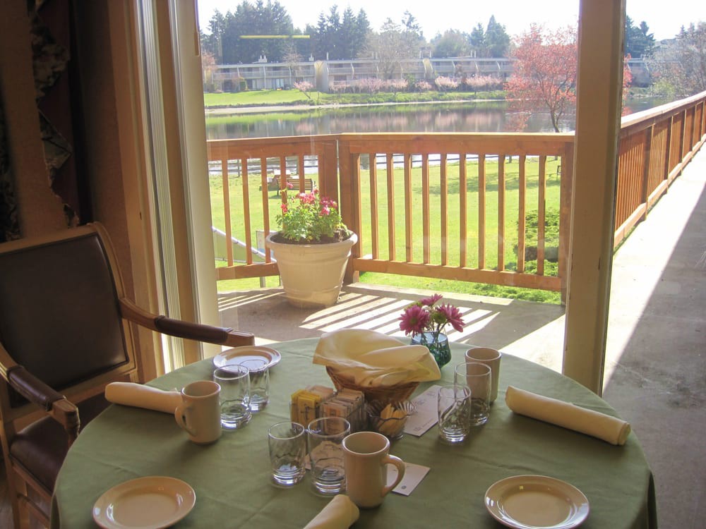 A dining table set for a meal with a view of a balcony and lush greenery in the background.