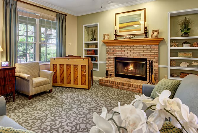 A cozy living room featuring a brick fireplace, piano, and comfortable seating.