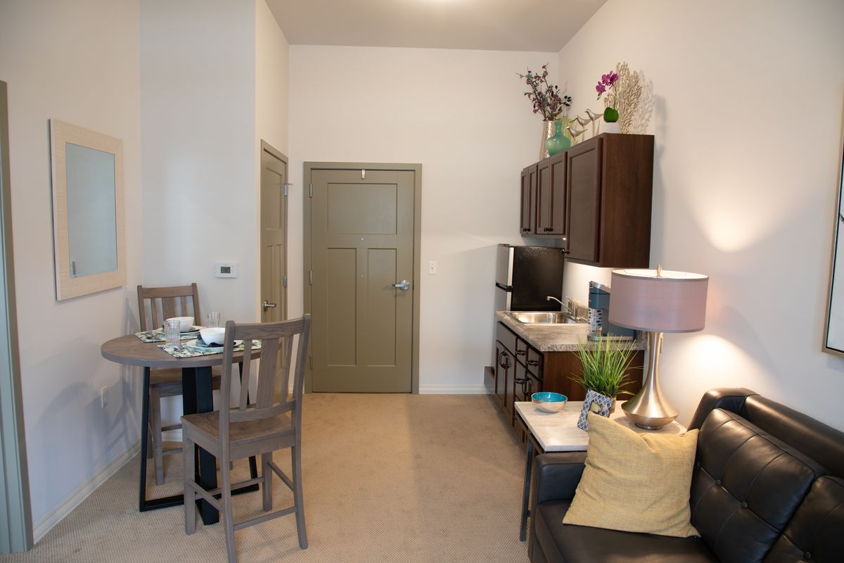 A modern apartment interior featuring a kitchenette, dining area, and living space.