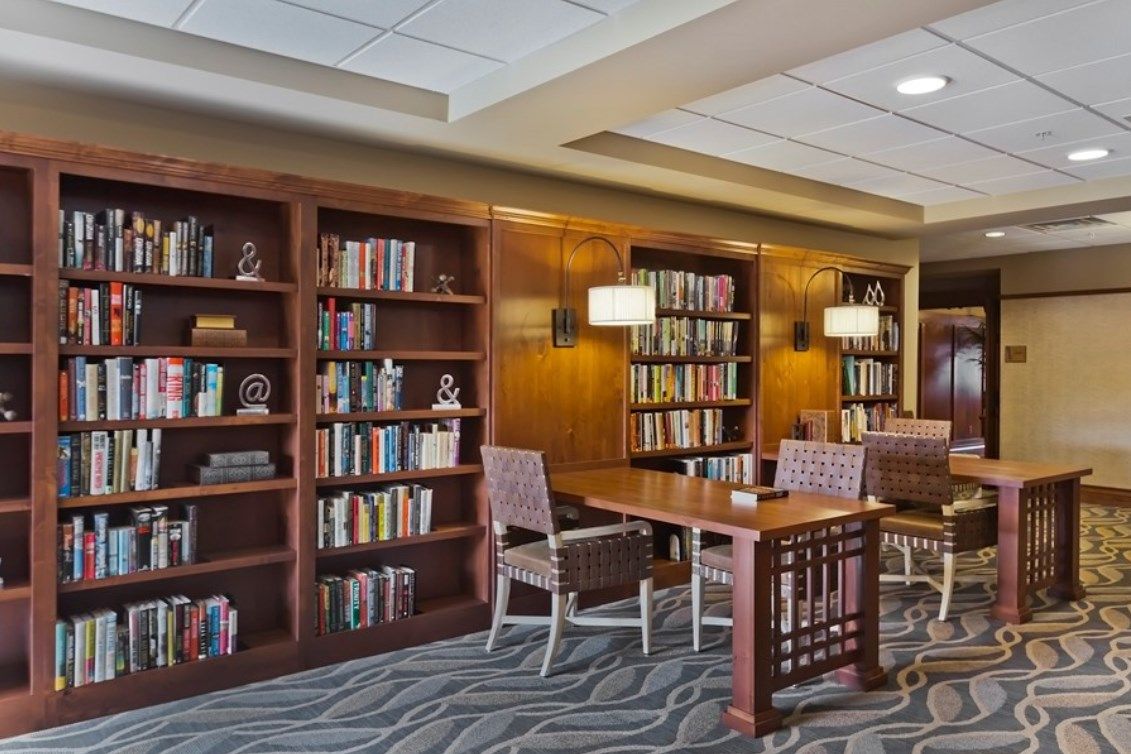 A cozy library corner with bookshelves, a reading table, and chairs.