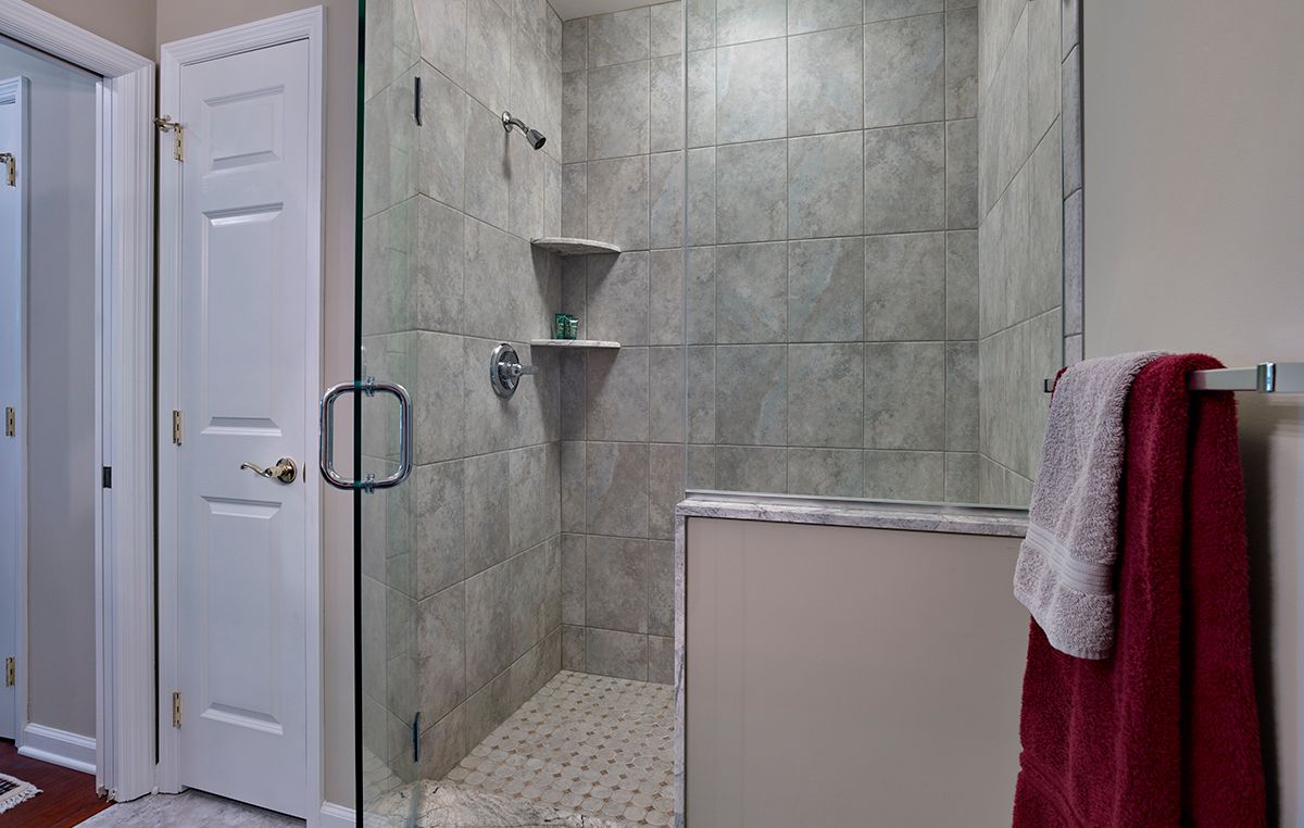 A modern tiled shower with a glass door and built-in shelves.