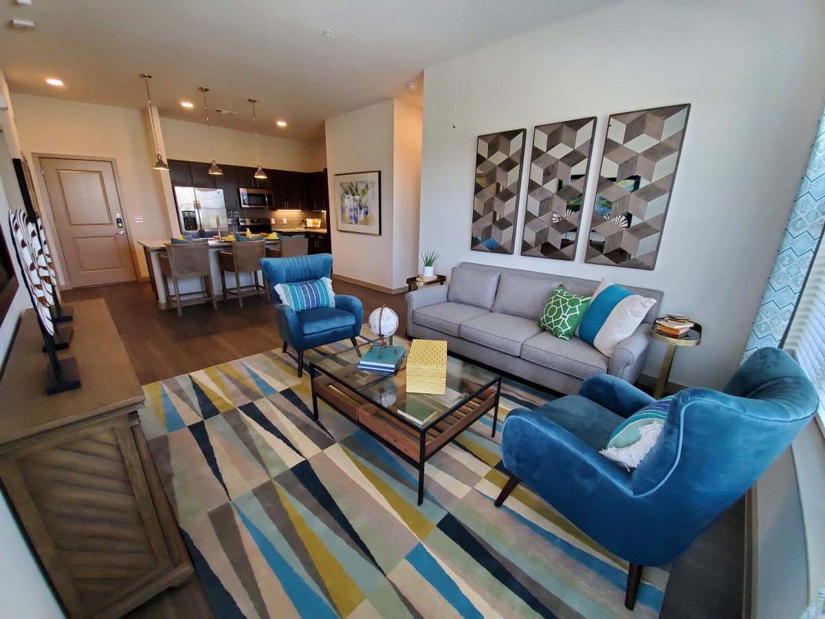 A modern living room with vibrant decor, featuring a comfortable sofa and armchairs, a colorful rug, and contemporary artwork.