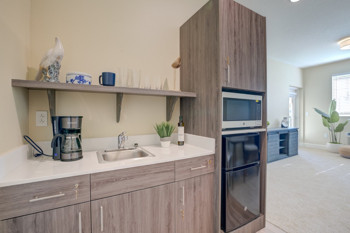 A modern kitchen with wood cabinets featuring a sink, coffee maker, and built-in oven and microwave.