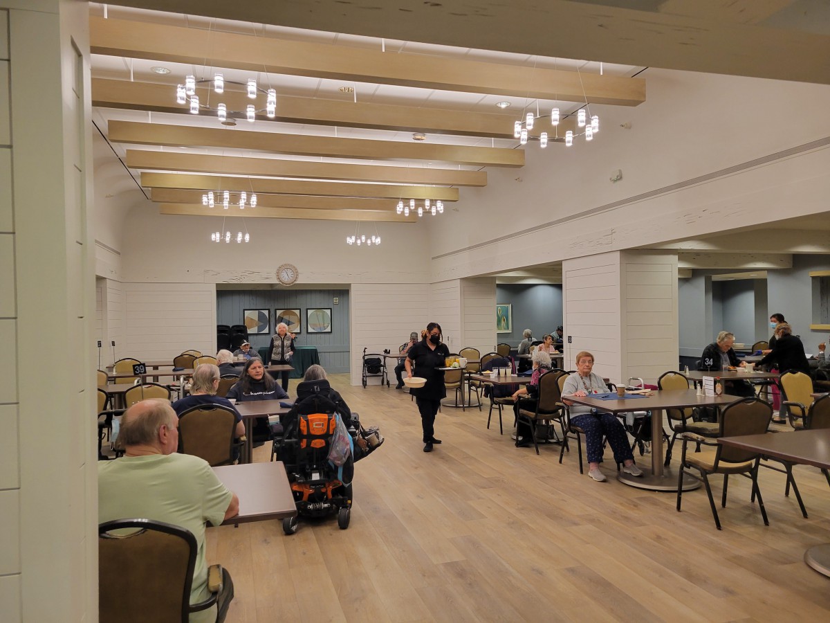 A community center with people seated at tables under warm lighting.