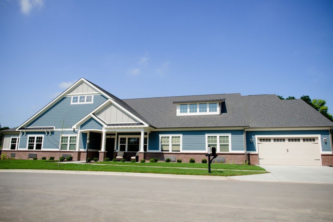 A suburban residential house with a spacious front yard and clear blue sky.