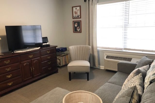 A cozy living room with a chair, sofa, and television.