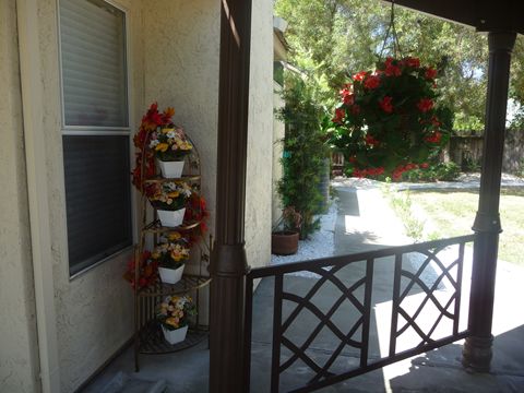A cozy porch adorned with a five-tier plant stand and a hanging basket full of vibrant flowers.