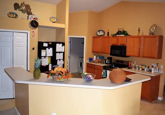 A cozy kitchen interior with wooden cabinets, a black refrigerator, and various decor items on the countertop.