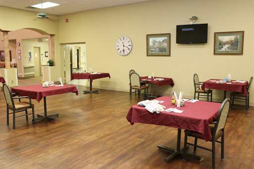 A spacious restaurant dining area featuring neatly arranged tables with red tablecloths and a warm, inviting atmosphere.