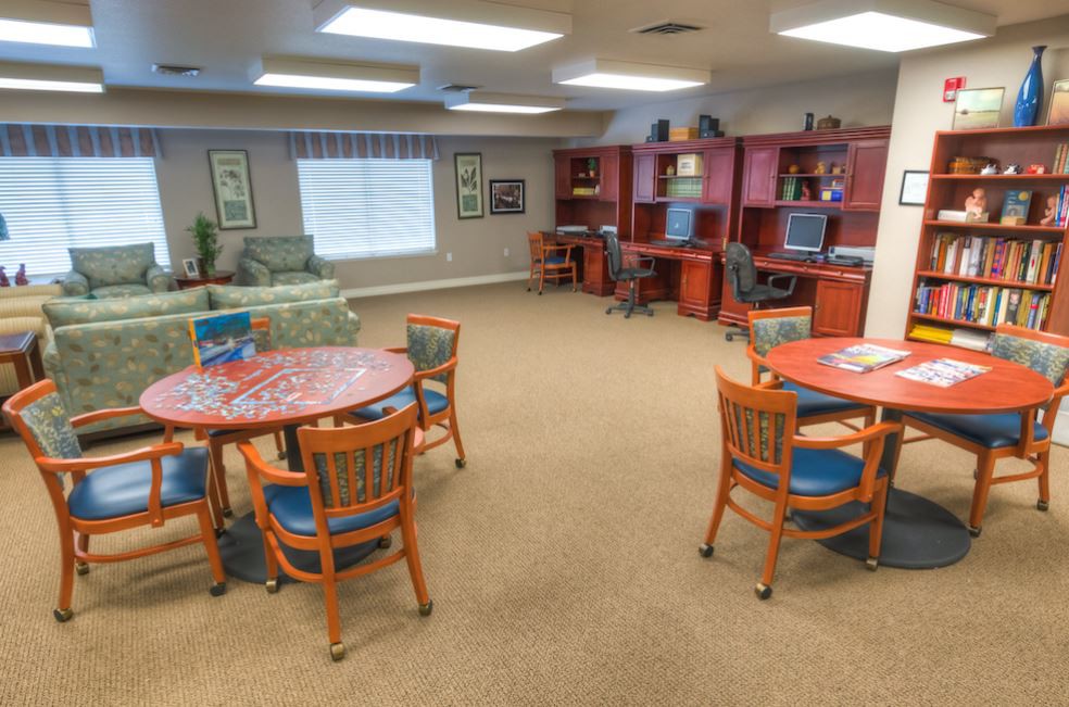 A quiet library space with reading tables, chairs, and computer stations.
