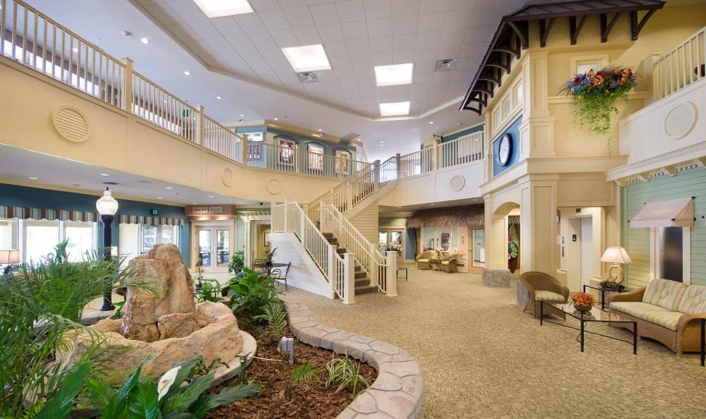 A modern lobby with a central staircase, indoor plants, and elegant lighting.