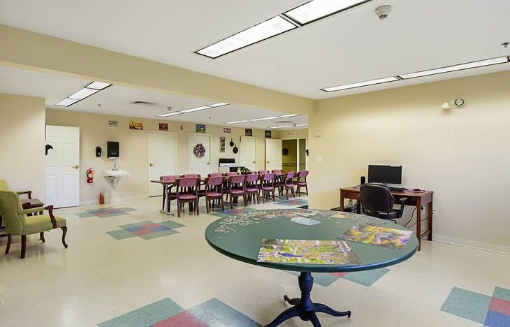 A spacious community room with tables, chairs, and a computer station.