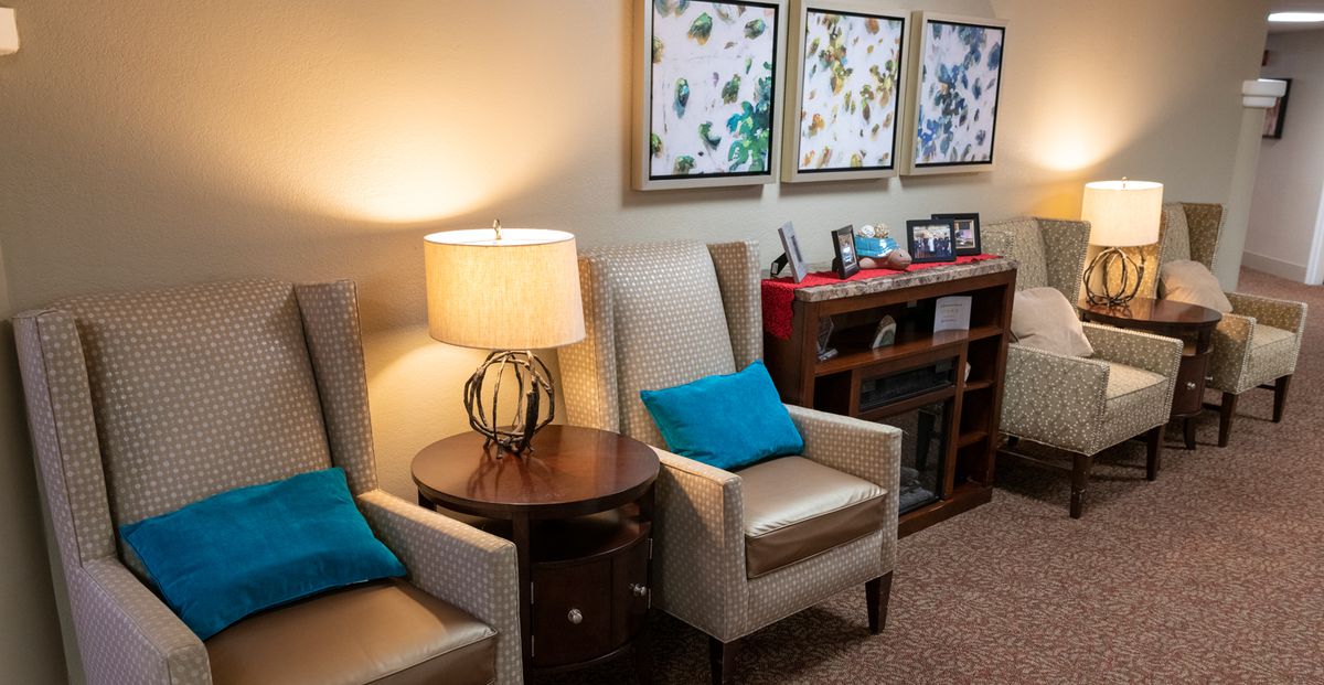 A cozy living room with comfortable chairs, a lamp, and decorative artwork on the wall.