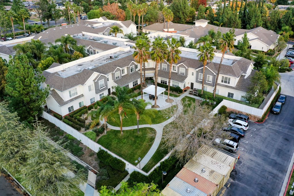 Aerial view of a residential complex with landscaped gardens and palm trees.