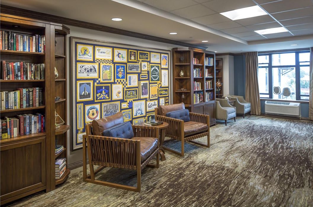 A cozy lounge with comfortable seating, an art-filled wall, and bookshelves for a relaxing atmosphere.
