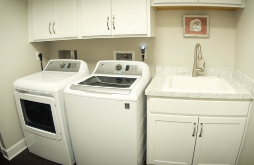 A clean and organized laundry room featuring a washing machine, dryer, and a utility sink.