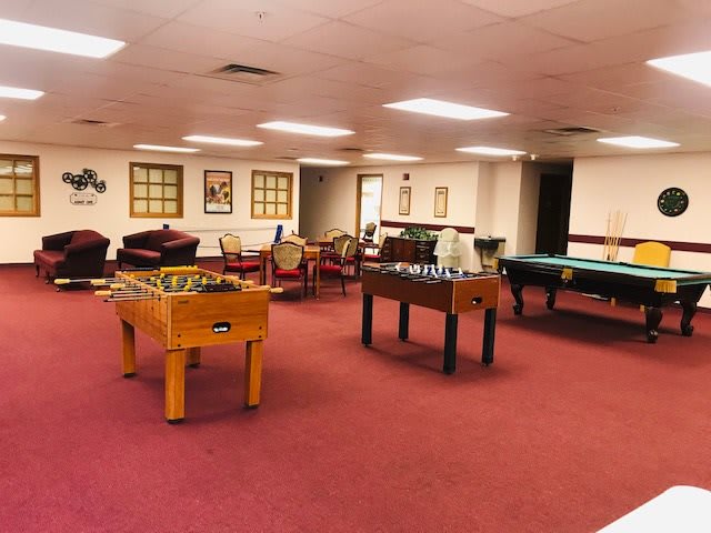A spacious game room featuring foosball and pool tables with comfortable seating areas.