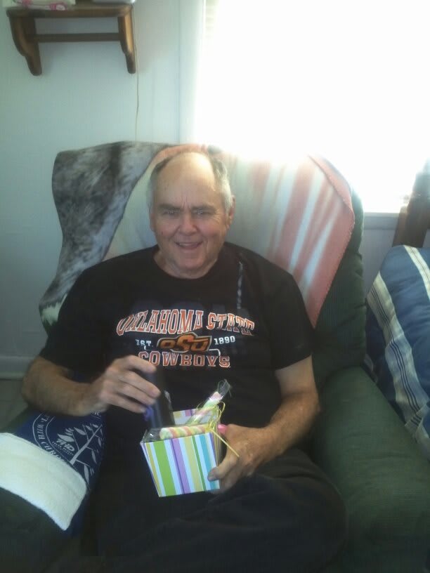 A man sitting and holding a gift, smiling indoors.