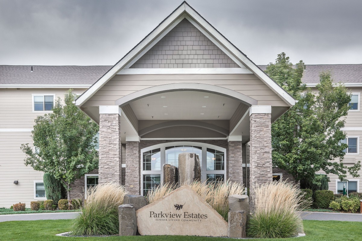 Entrance of a modern building with a welcoming sign and landscaped surroundings.