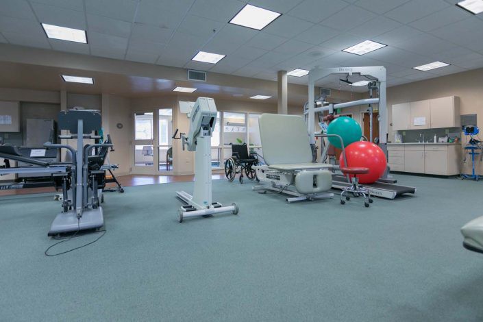 A physical therapy room equipped with gym equipment and exercise balls.