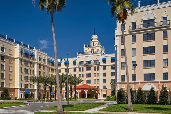 A grand hotel with elegant architecture surrounded by palm trees under a clear blue sky.