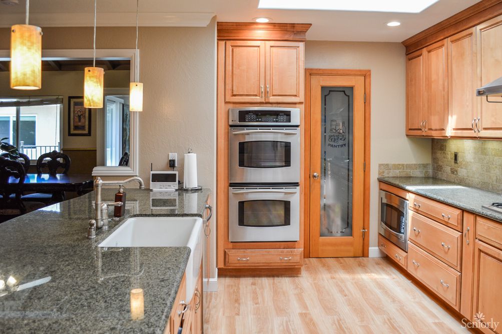A modern kitchen featuring wood cabinets, granite countertops, and a double oven.