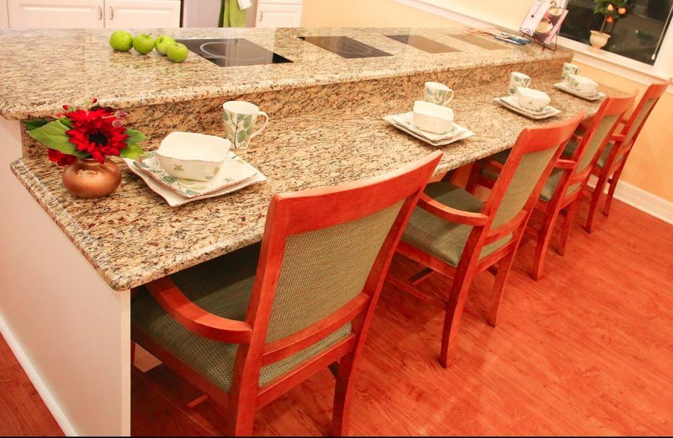 A kitchen bar counter with granite top and neatly arranged place settings.