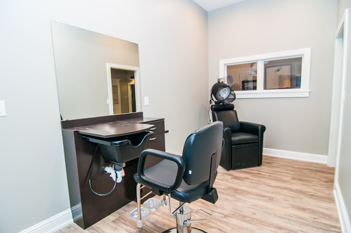 A cozy and modern hair salon setup featuring a styling station, a barber chair, and a hair dryer.