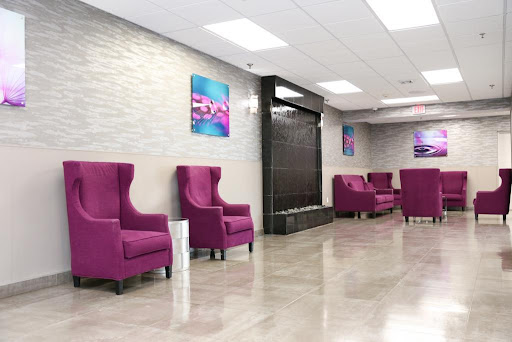 A stylish and modern lobby featuring purple chairs and a calming water feature.