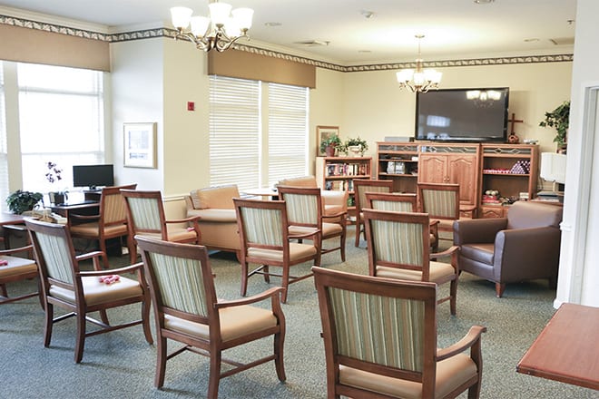 A spacious lounge area with arranged chairs and a television for guests.