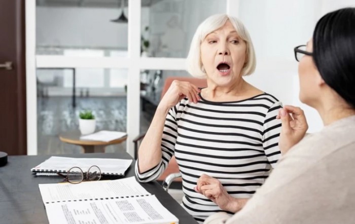 Surprised senior woman in an office setting during a conversation.