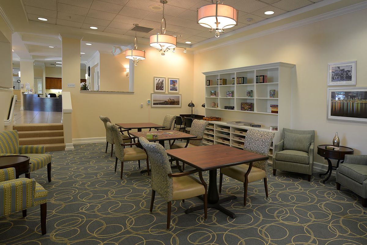 A well-lit dining area with tables, chairs, and bookshelves.