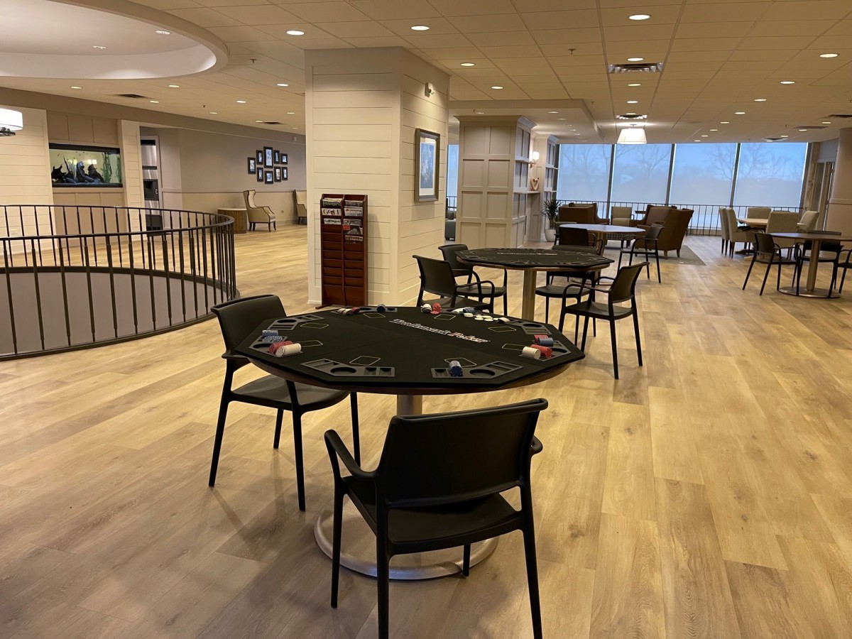 A modern lounge area with tables and chairs on wooden flooring.