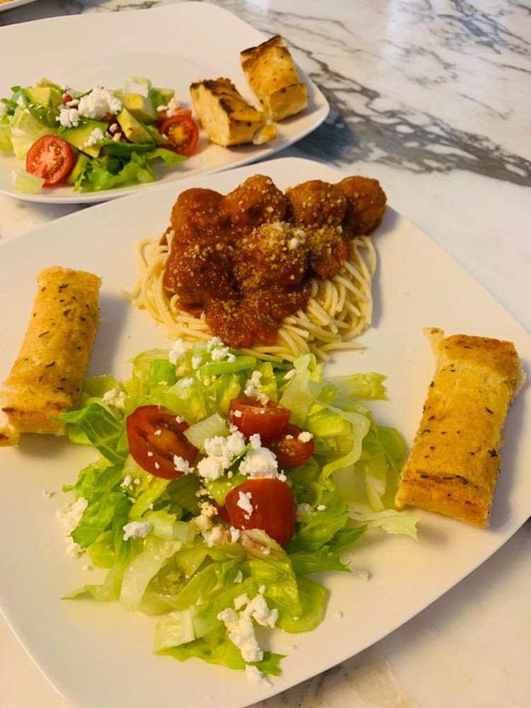 A delicious Italian meal featuring spaghetti with meatballs, fresh salad, and crispy garlic bread.