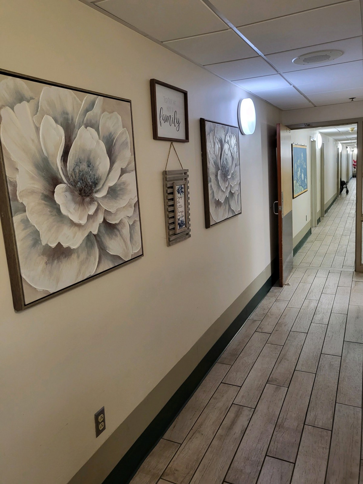 A hallway decorated with framed floral artwork and other wall hangings.