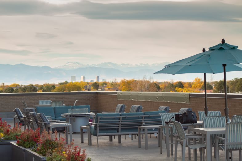 A scenic outdoor patio with seating and umbrellas, offering a picturesque view of the landscape and sky.