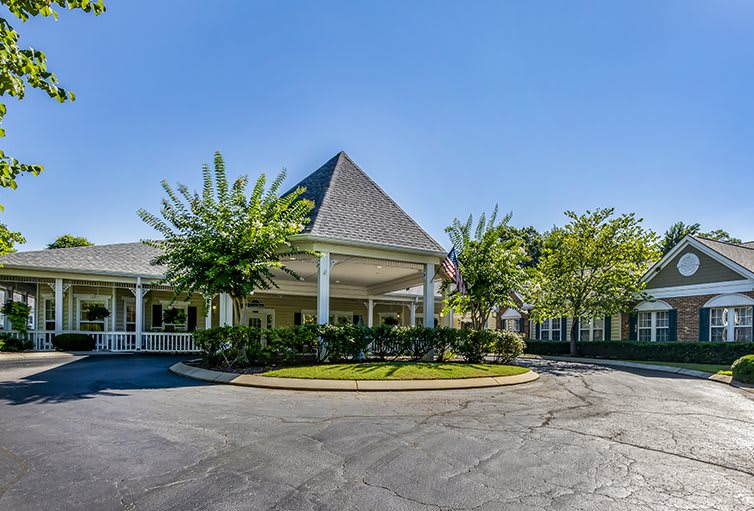 A view of a building entrance surrounded by trees and a circular driveway.