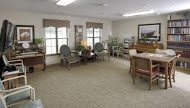 A cozy waiting room with several chairs, windows, and a carpeted floor.