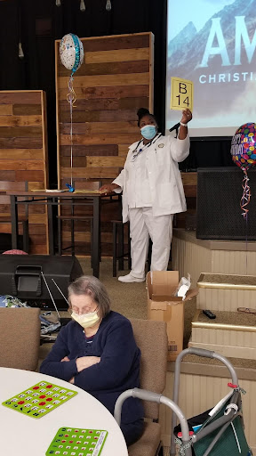 A healthcare worker addresses the audience during a celebration event, emphasizing safety with masks.