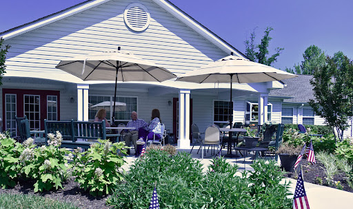 A cozy outdoor seating area featuring umbrellas, surrounded by lush greenery and flowers.