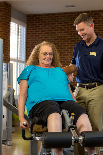 A personal trainer assists an older adult in a fitness session at the gym.
