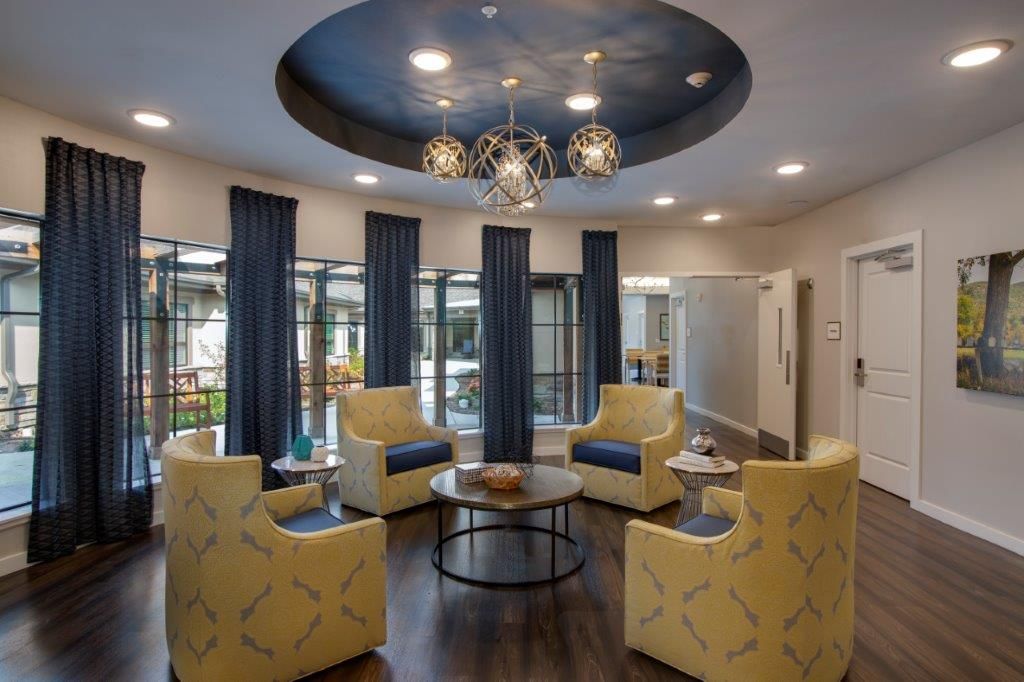 A modern lobby with blue and yellow seating, featuring a stylish chandelier and a round center table.
