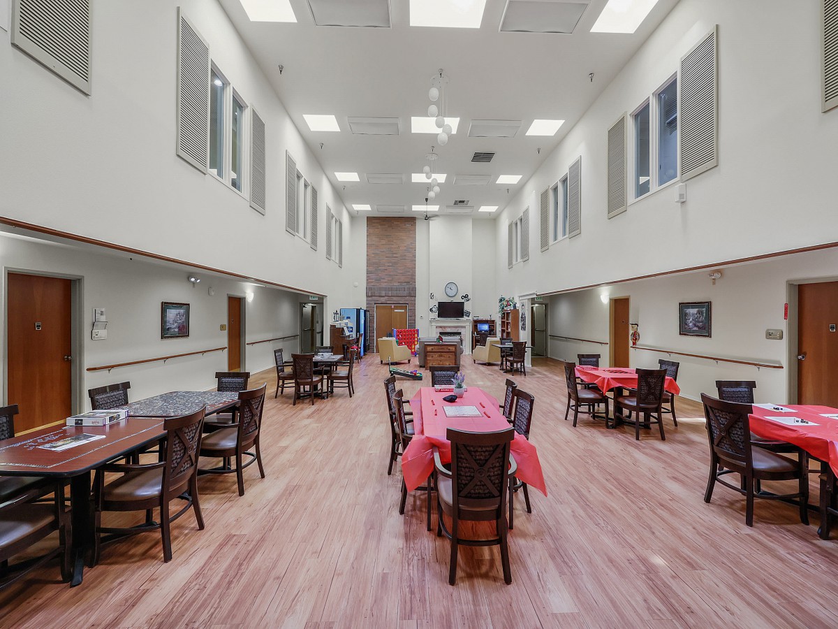 A spacious dining hall with tables and chairs arranged neatly, featuring high ceilings and decorated tables.