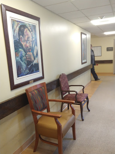 A quiet hallway featuring chairs and artwork, creating a welcoming waiting area.