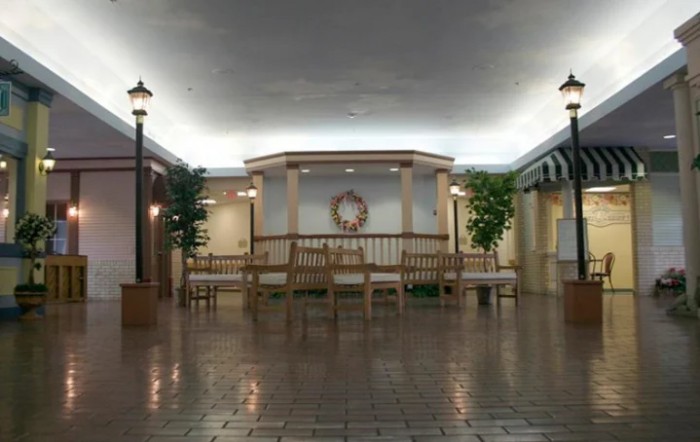 A quiet indoor mall area featuring benches, decorative lamps, and plants.