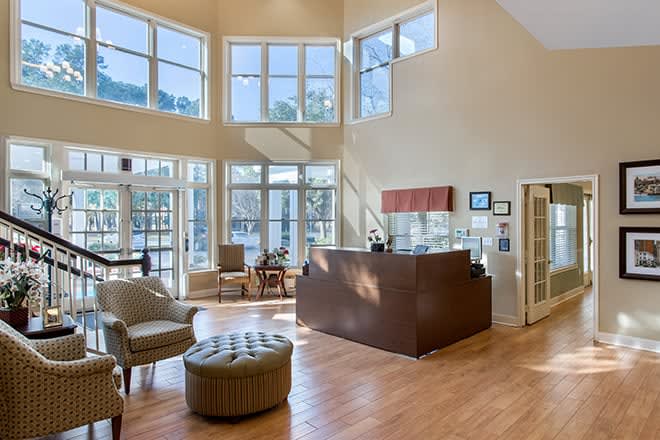 A spacious and modern reception area with large windows allowing ample natural light, featuring comfortable seating and a sleek wooden reception desk.