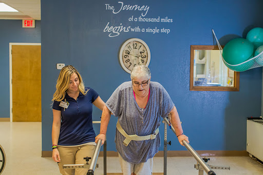 A patient receives support while practicing walking with the help of a therapist in a rehabilitation setting.